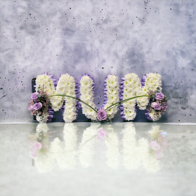 Mum Funeral Letters - The frame is edged in a pleated ribbon and filled in with a chrysanthemum base. The clusters generally consist of roses and other seasonal flowers.