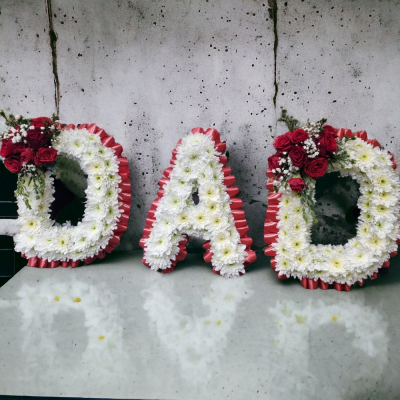 Funeral Lettering - The frame is edged in a pleated ribbon and filled in with a chrysanthemum base. The clusters generally consist of roses and other seasonal flowers.