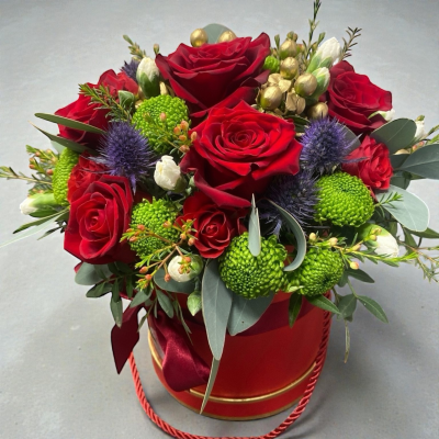 Nutcracker Hatbox - A luxurious Christmas hatbox arrangement featuring red roses, white blooms, green chrysanthemums, purple thistles, golden accents, and lush seasonal foliage.