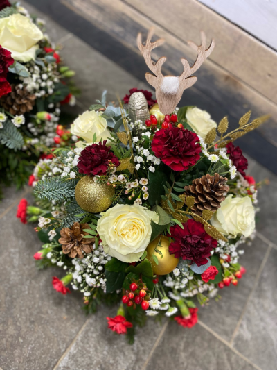 Christmas Posy - A festive Christmas posy featuring white roses, burgundy carnations, pinecones, gold baubles, red berries, and a charming wooden reindeer topper.